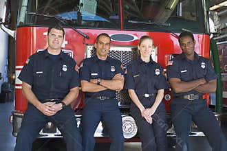 Portrait of firefighters standing by a fire engine