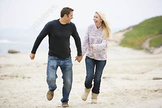 Couple running at beach holding hands