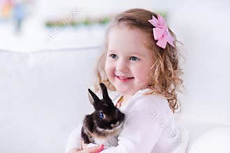 Little girl playing with a real pet rabbit