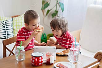 Two happy kids, two brothers, having healthy breakfast sitting a