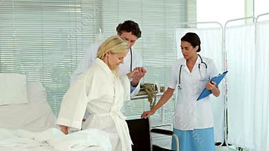 Doctors helping patient to sit on wheelchair