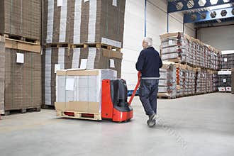 Worker Pushing Handtruck Loaded With Goods