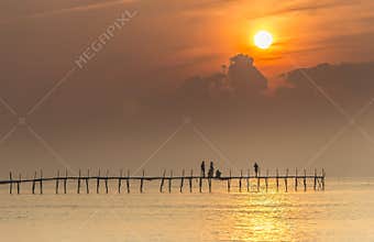 Family welcome sunrise on wooden bridge