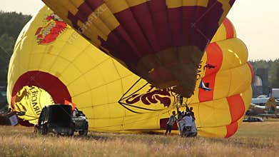Yellow hot air balloon is prepared for flight in field