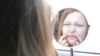 Beauty model teenage girl looking in the mirror and checking her skin, applying make up. 4K