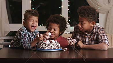 Three afro boys eating cake.