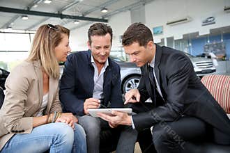 Couple making a digital signature on tablet in car shop
