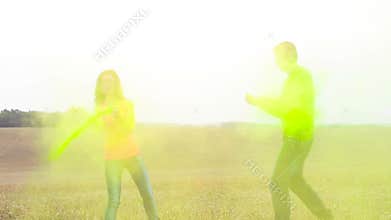 Young and beautiful, hipster couple funny playing in the field on holi color festival throw each other with colour paint