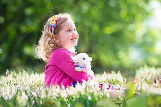 Little girl playing with bunny on Easter egg hunt