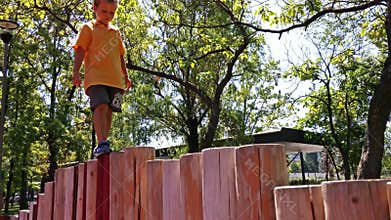 Little boy walking on wooden pillars