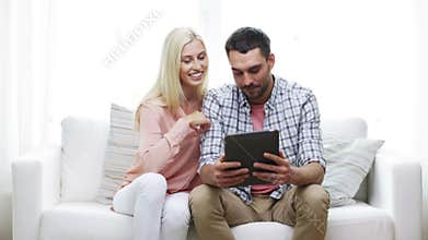 Happy couple with tablet pc viewing photos at home