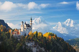 Germany. The famous Neuschwanstein Castle in the background of snowy mountains and trees with yellow and green leaves.
