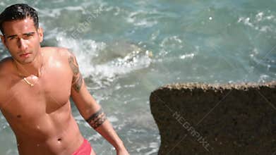 Young man standing in water by sea or ocean shore,