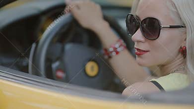 Blonde in sits behind the wheel of cabriolet