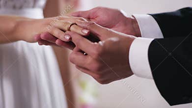 Gold wedding rings and hands of just married couple Close up on hand of a man put on an engagement ring on the finger