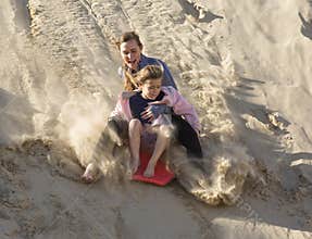 Adventuresome girls boarding down the Sand Dunes