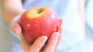 Young woman holding out an apple