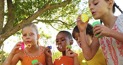Group of kids blowing bubbles in park