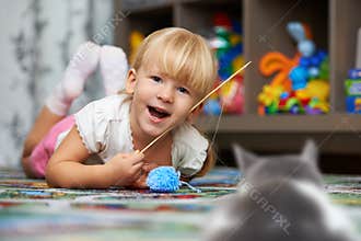 Child playing with a cat on the floor in the children`s room