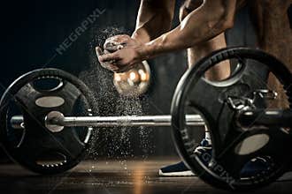 Young athlete getting ready for weight lifting training. Powerlifter hand in talc preparing to bench press