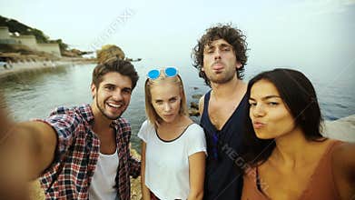 Young people taking selfies on the beach.