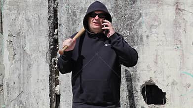 Man with a baseball bat talking on smart phone