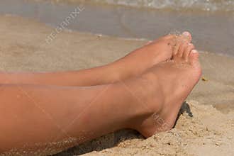 Holiday concept. Woman feet close-up relaxing on beach, enjoying sun