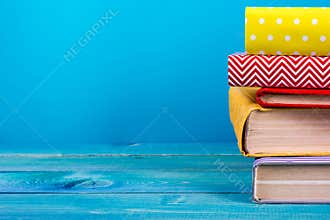 Stack of colorful books, grungy blue background, free copy space