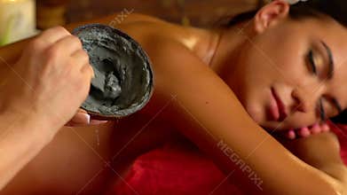 Massage and clay body mask in spa salon. Slow motion.