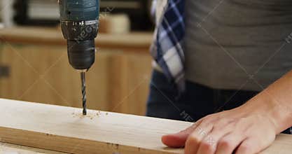 Focus on carpenter drilling a wooden plank