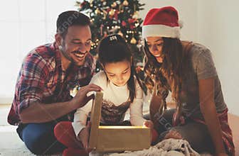 Cute girl opening a present on a Christmas morning with her family
