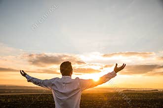 Thankful Businessman with Open Arms at the Field on sunset