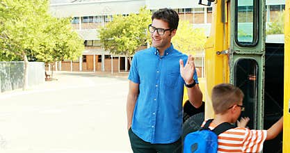 School kids giving high five to teacher while entering the bus