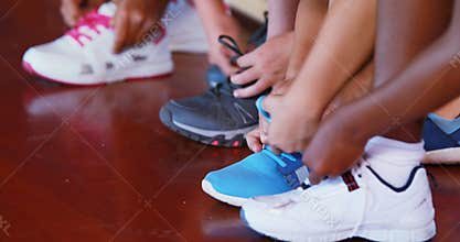Girls tying shoe laces in basketball court