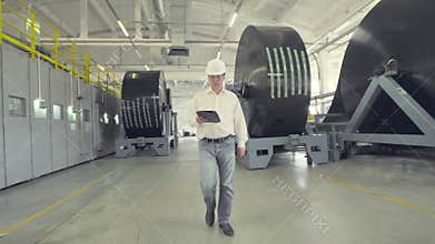 Engineer in hard hat walking through factory