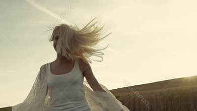Smiling girl with beautiful hair runs cross the field of golden wheat. Slow motion, stabilizer shots. Joy of life.