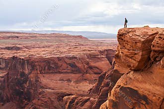 Man stands on top of a mountain. Hiker with backpack standing on a rock, enjoying valley view, Arizona