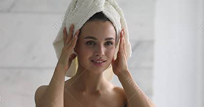 Happy attractive young woman with towel on head touching face