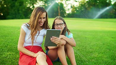 Cute girl and woman waving hands at camera on digital tablet outdoors