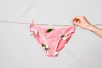 Woman hangs underwear with flowers on clothesline, concept content for feminist blog, poster about women`s health