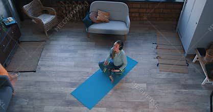 Top view meditation and stress relief. Beautiful sporty young woman doing yoga with smart phone app on self isolation.