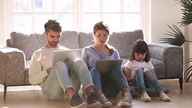 Mother father and little daughter sitting on floor with devices