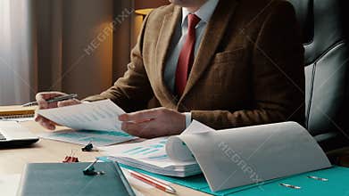 A businessman in a suit works with business charts and financial reports. Work with documents in the office.