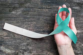 Teal and white ribbon for Cervical Cancer awareness campaign concept symbolic bow color on woman helping hand support on old aged