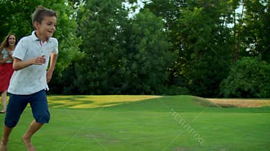 Mother throwing ball in green field. Parents and kids playing with ball in park