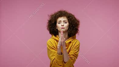 Please, I`m begging! Upset girl afro hairstyle in hoodie appealing to camera with pleading imploring eyes, keeping prayer gesture