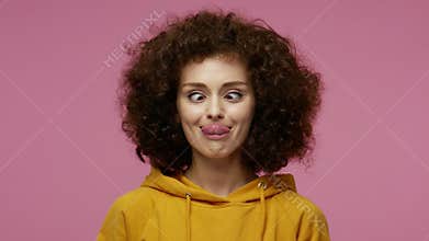 Funny amusing girl afro hairstyle in hoodie looking awkward with crossed eyes and puffed cheeks, fooling around