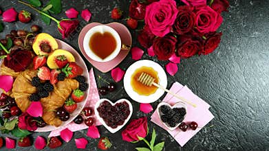 Romantic indulgent breakfast with croissants, pancakes, waffles fruit and roses.
