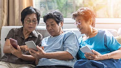 Ageing society concept with Asian elderly senior adult women sisters using mobile digital smart phone application technology
