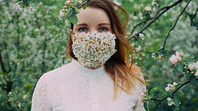 Young girl with blue eyes in the flower mask in the cherry orchard.